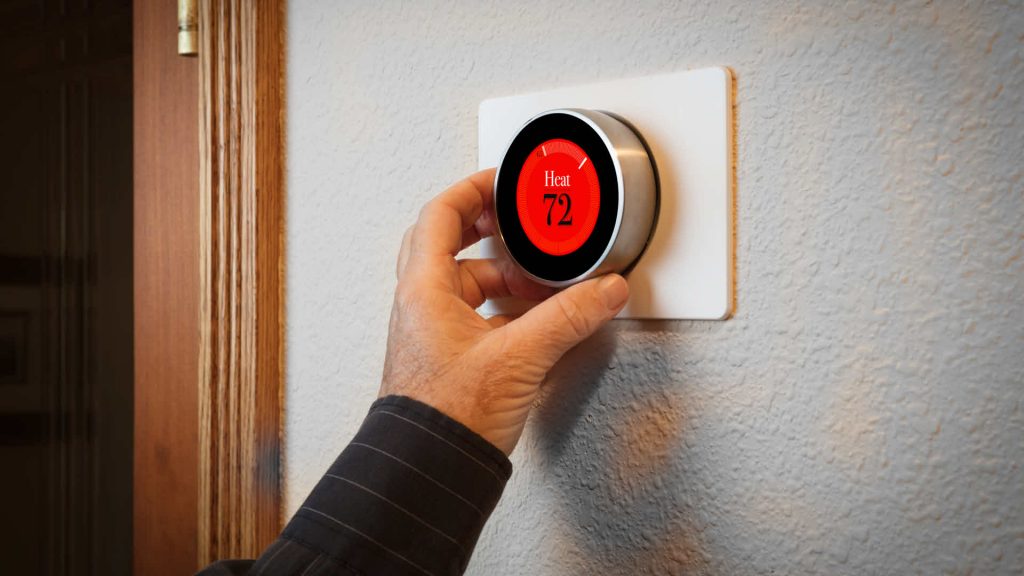 Hand adjusts a smart thermostat.