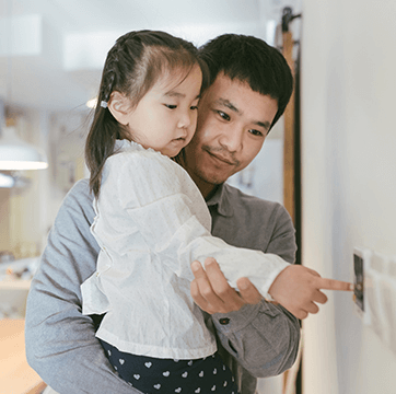 Father holding daughter who is pointing at wall
