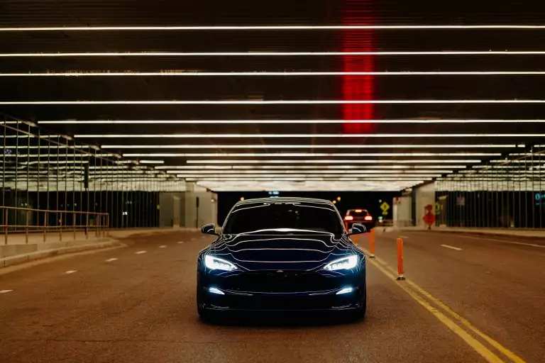 EV driving through lit up tunnel at night