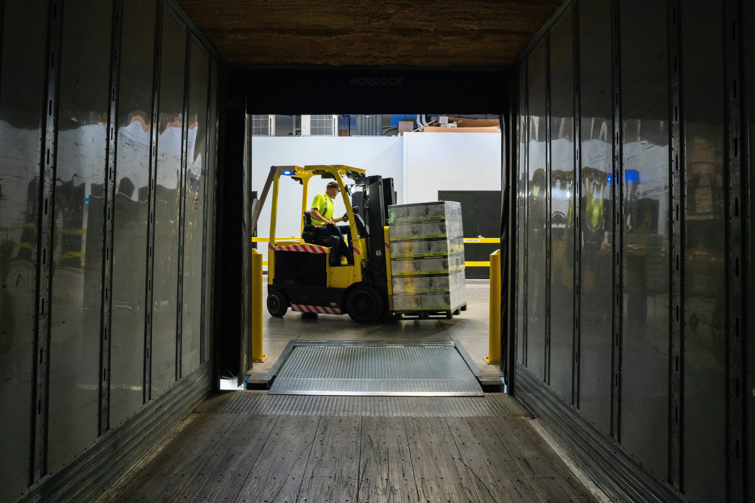 forklift carrying stacks of boxes at the end of a hallway