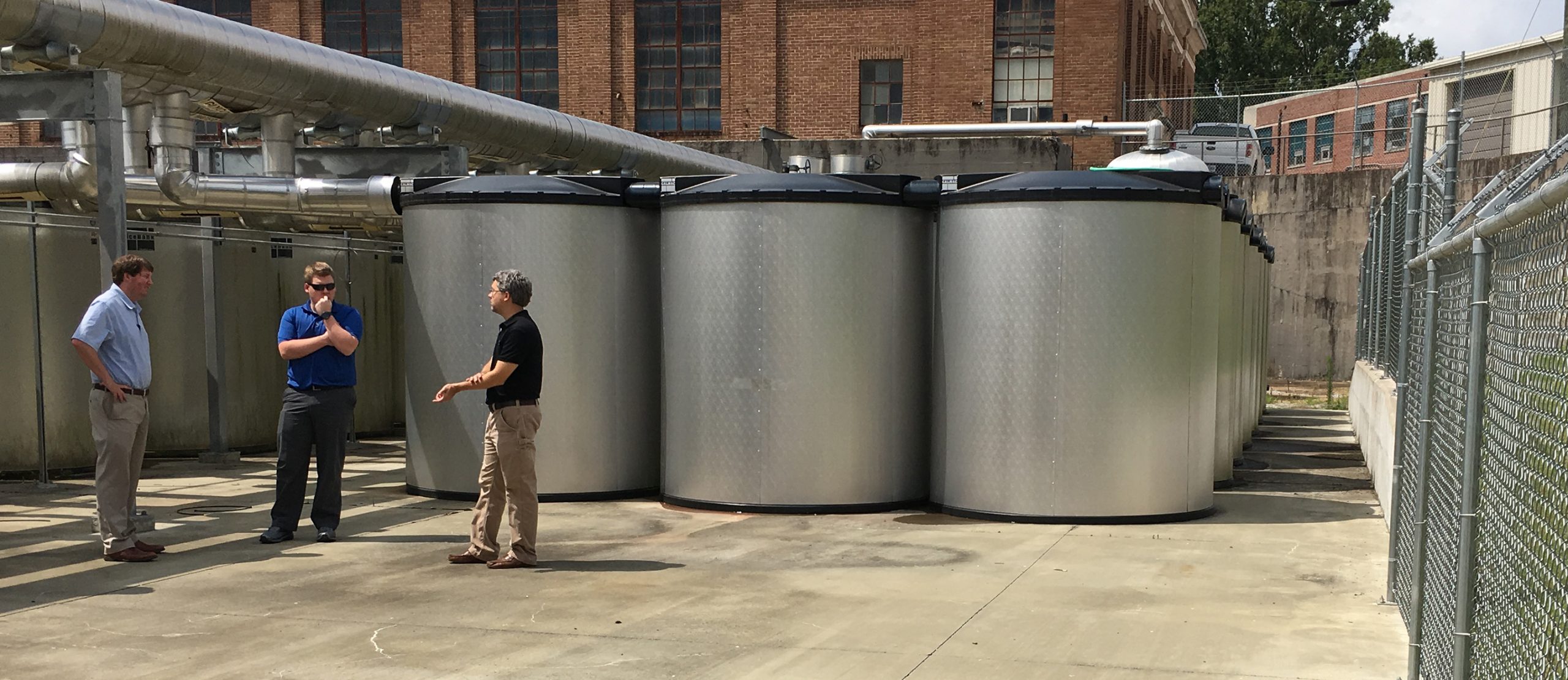 a group of men talking outside in front of industrial thermal ice storage unit