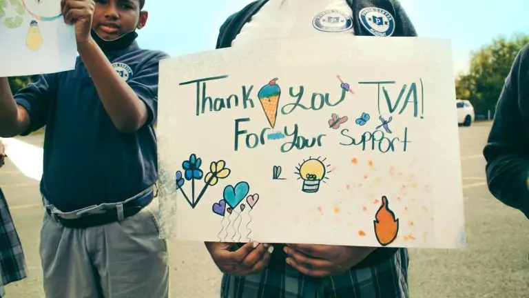 Student holds a handmade sign thanking TVA for its support.