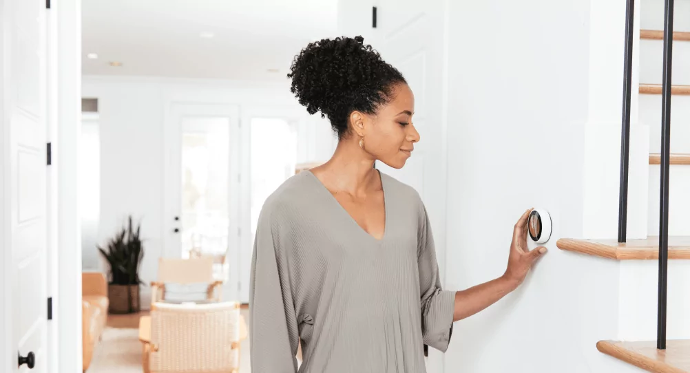 Woman adjusting a smart thermostat