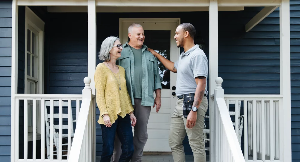 Smiling husband and wife standing on their porch with a member of TVA EnergyRight's Quality Contractor Network.