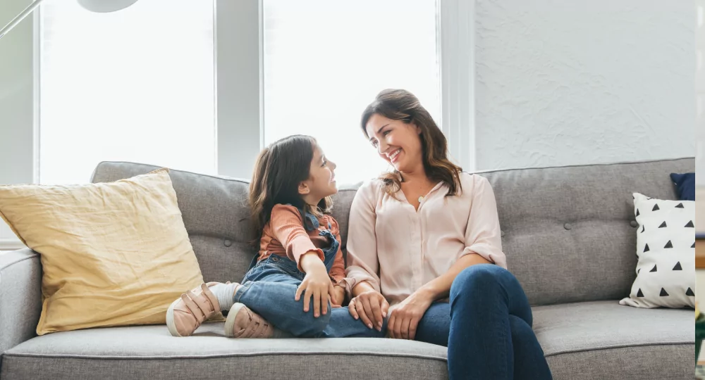 Smiling mother and daughter sitting on a couch.