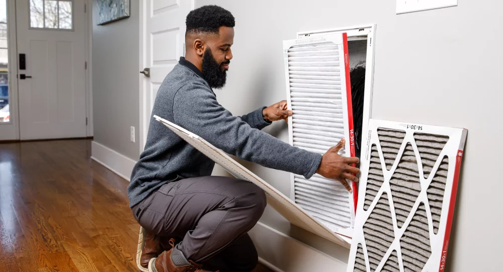 Man replacing an air return filter in his home.