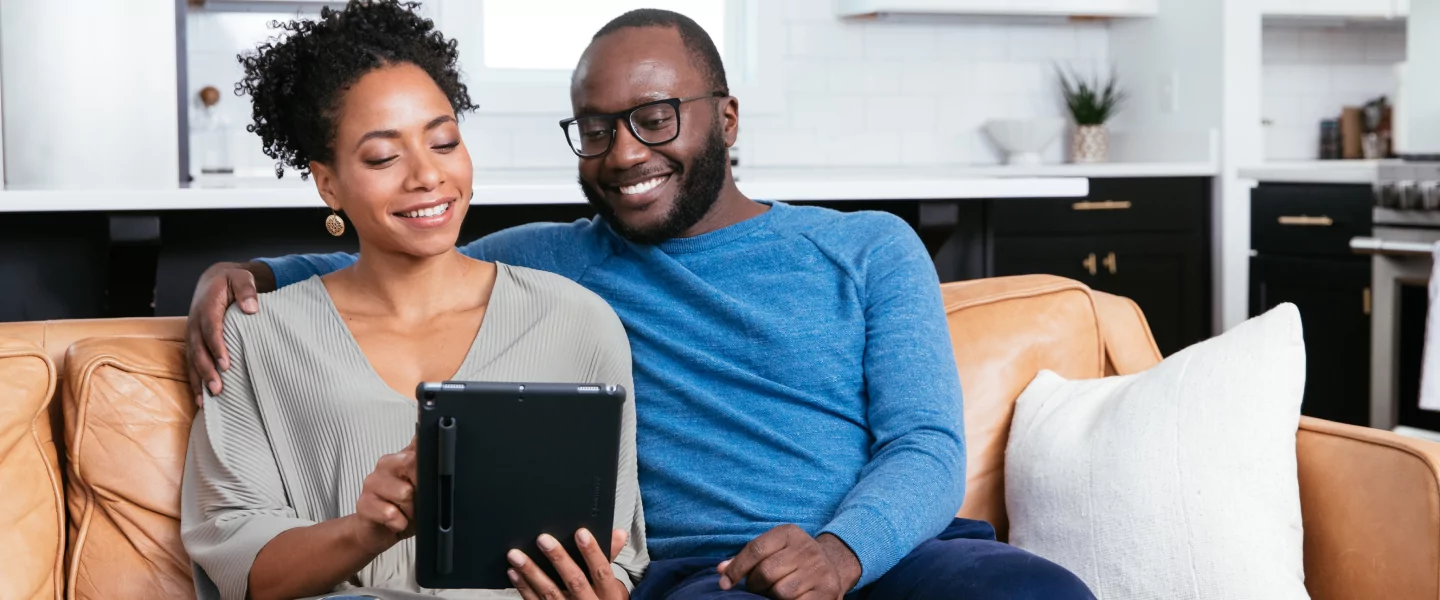 Smiling couple, sitting on couch.