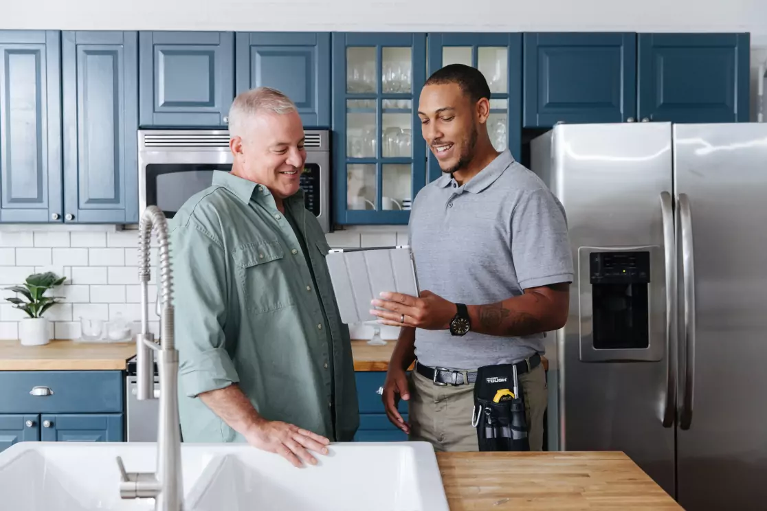 Two men discussing energy efficiency in a kitchen.