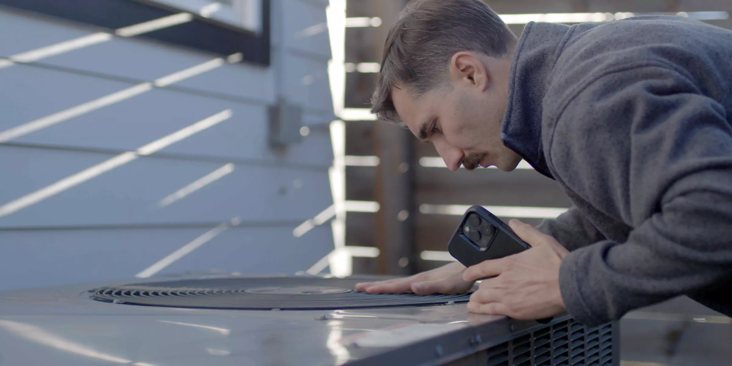 man inspecting heat pump