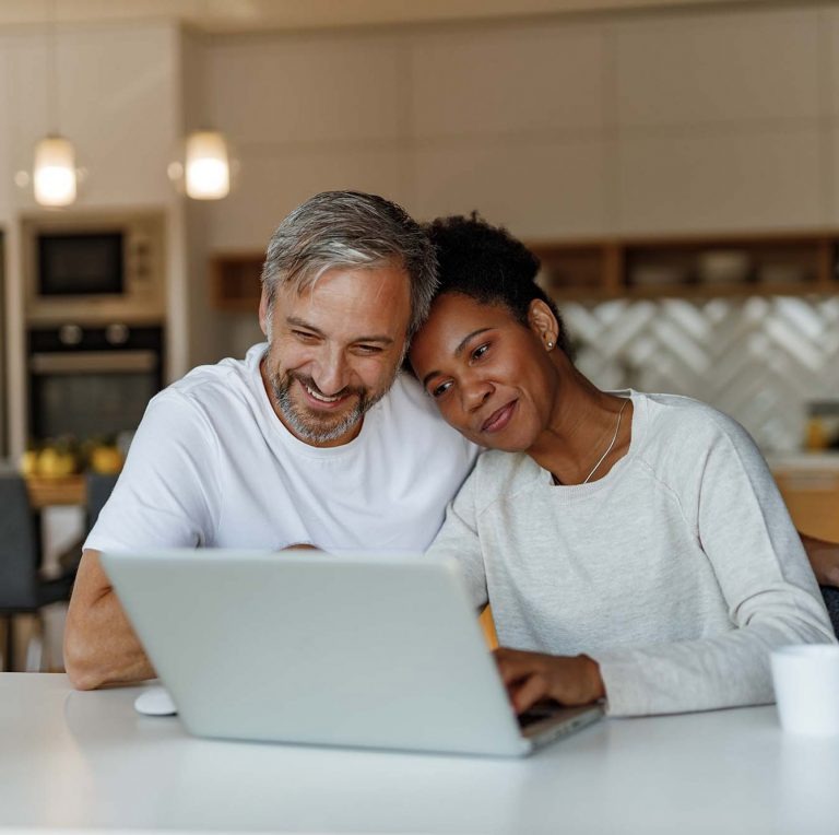 Couple reading computer in kitchen.