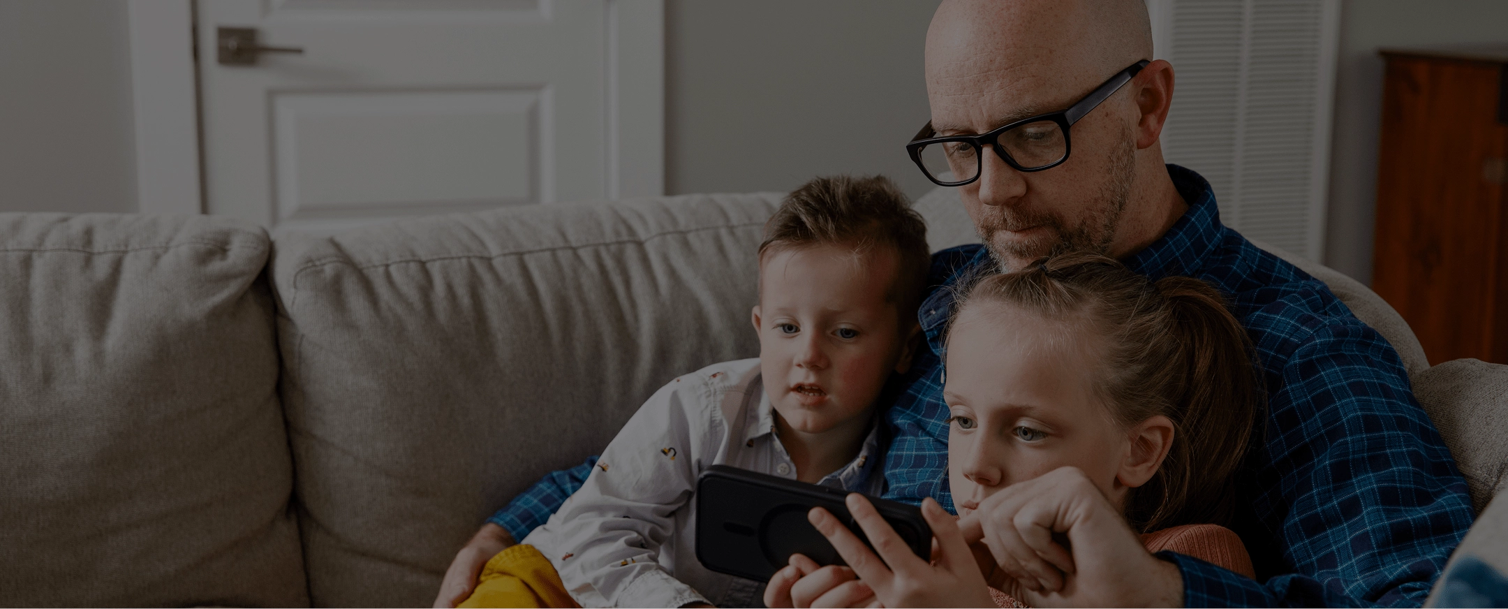 Father and kids on a couch, looking at a tablet and signing up for Green Switch.