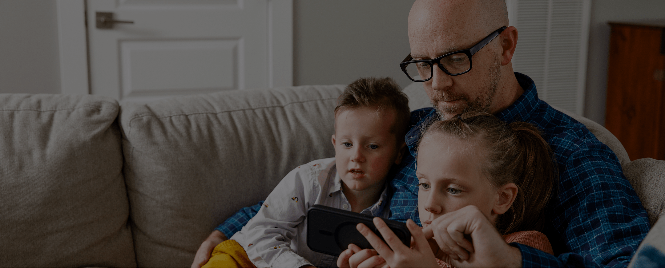 Father and kids on a couch, looking at a tablet and signing up for Green Switch.