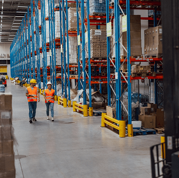Two workers walking in a warehouse.
