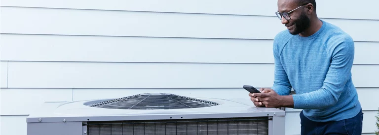 A homeowner inspecting an outdoor residential heat pump split-system unit.