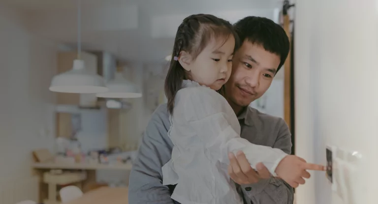 Little girl in her dad's arms, turning off the lights.