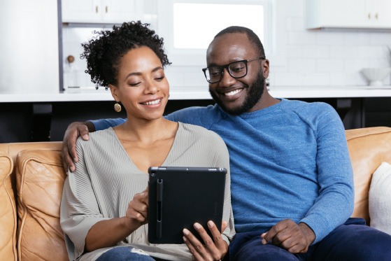 Couple sitting on a couch reviewing information on a tablet together
