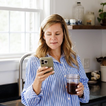 Homeowner checking information on a smartphone while standing in a kitchen