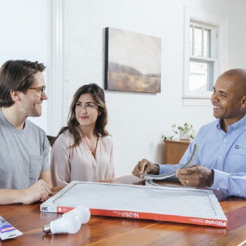 Technician reviewing documents with homeowners at a table during a home consultation