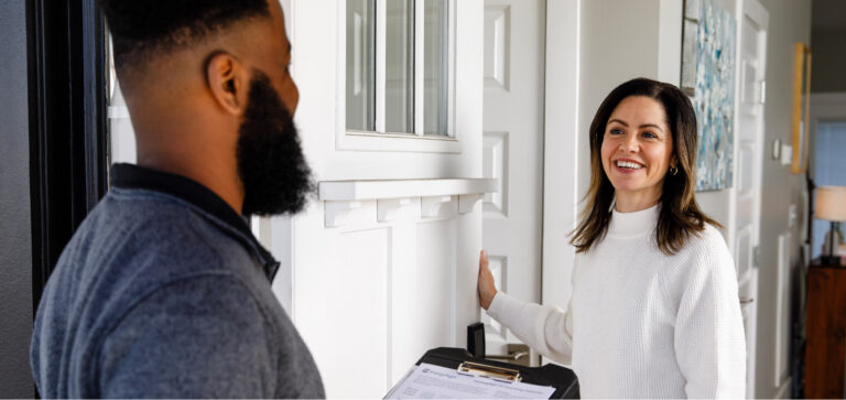 A smiling homeowner welcomes a TVA Energy Exper at her front door.