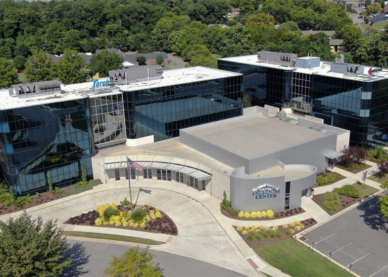 High-angle exterior view of the Freedom Center commercial building complex featuring reflective glass windows, rooftop commercial HVAC equipment, and corporate signage for Torch Technologies and Freedom Center.