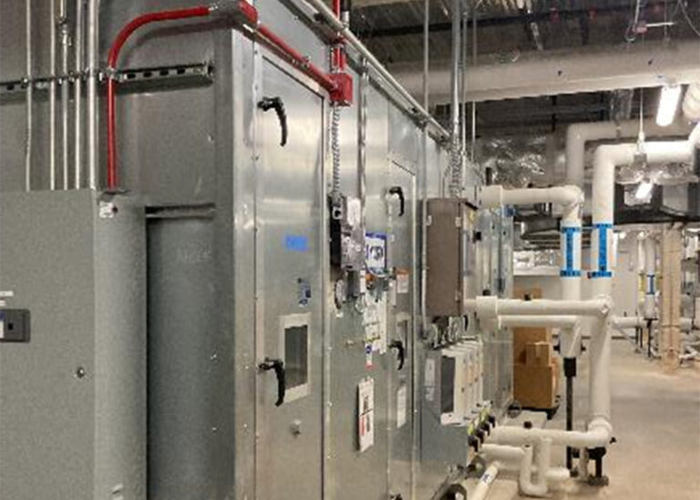 A large, high-efficiency commercial HVAC air handling unit at Methodist University Hospital with galvanized steel panels and insulated piping systems inside a mechanical room.