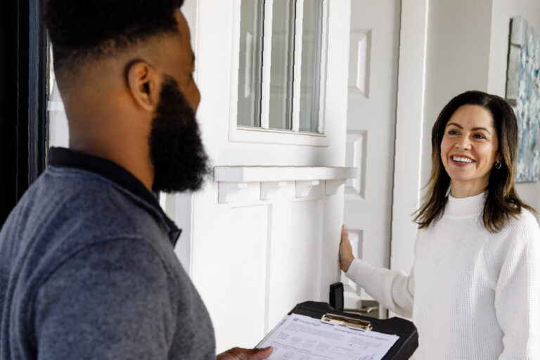 A smiling homeowner welcomes a TVA Energy Exper at her front door.