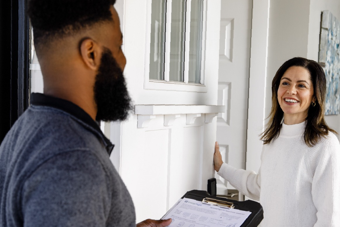 A smiling homeowner welcomes a TVA Energy Exper at her front door.