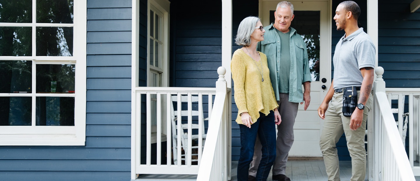 A TVA Energy Expert talking with a couple on the front porch of a home during a residential energy consultation.