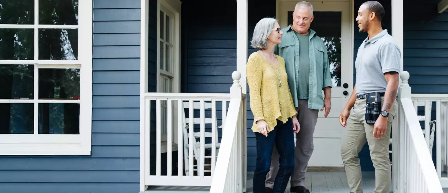 A TVA Energy Expert talking with a couple on the front porch of a home during a residential energy consultation.