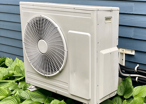 Modern outdoor heat pump unit installed at a home, promoting energy efficiency for year-round comfort and savings.