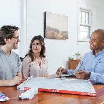 A TVA Energy Expert discusses energy-efficient HVAC air filters and LED light bulbs with a smiling couple, empowering smart home choices.