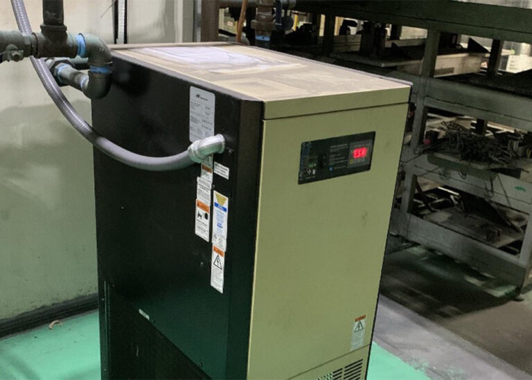 An industrial compressed air dryer system with a digital control display installed on a manufacturing facility floor.