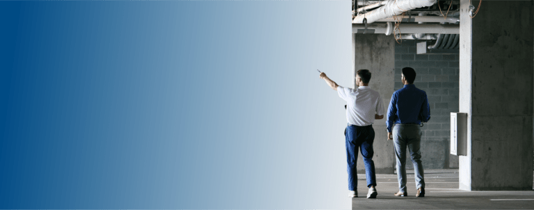 Two TVA Energy Experts inspect a commercial utility space, one pointing left, planning energy efficiency upgrades.