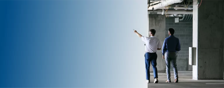 Two TVA Energy Experts inspect a commercial utility space, one pointing left, planning energy efficiency upgrades.