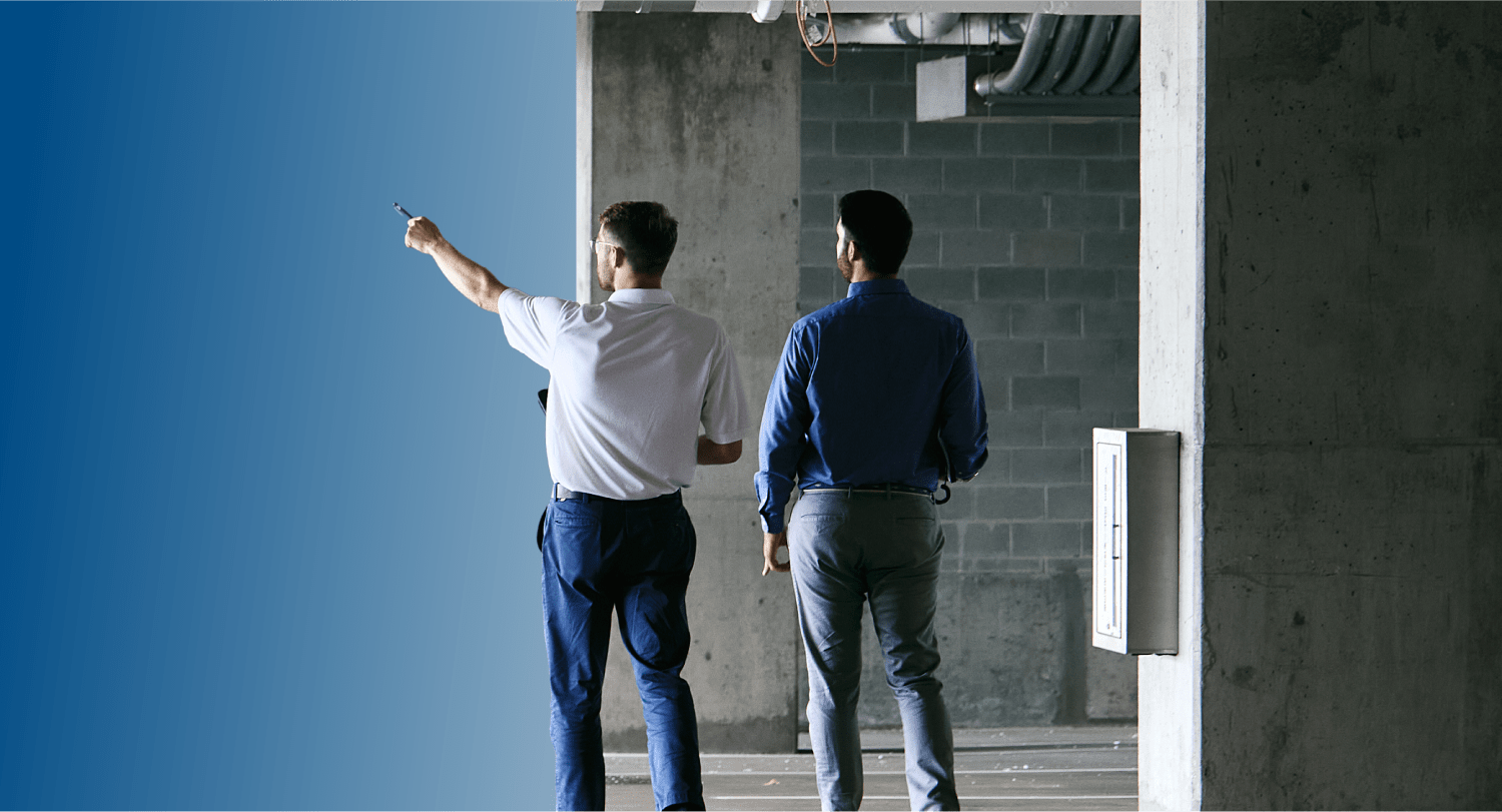 Two TVA Energy Experts assess an unfinished commercial site, one pointing towards potential energy-efficient upgrades.